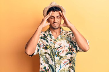 Elleri kafasında yaz şapkası takan genç İspanyol bir adam, stresten baş ağrısı çekiyor. migren ağrısı. 