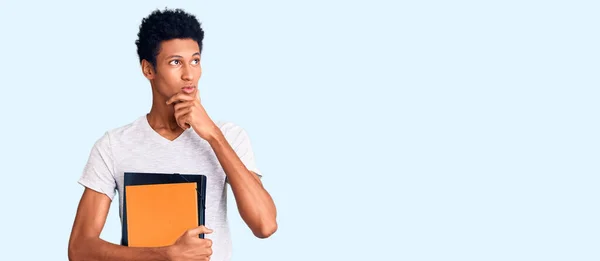 Jovem Afro Americano Segurando Livro Rosto Sério Pensando Sobre Questão — Fotografia de Stock