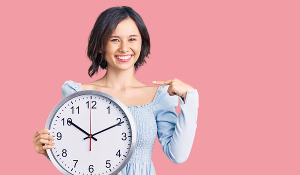 Giovane Bella Ragazza Tenendo Grande Orologio Puntando Dito Verso Sorridente — Foto Stock