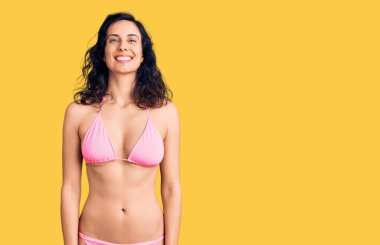 Yüzünde mutlu ve havalı bir gülümseme olan bikini giyen genç ve güzel bir İspanyol kadın. şanslı kişi. 