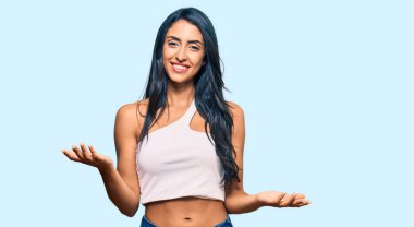 Güzel İspanyol kadın gündelik kıyafetler giyiyor neşeli kollarını açıp gülümsüyor. Hoş geldin, olumlu ve kendinden emin selamlar. 