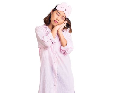 Genç, güzel Çinli kız uyku maskesi ve pijama giyerek uyur. Yorgun düşler kurar, el ele poz verir ve kapalı gözlerle gülümserdi.. 