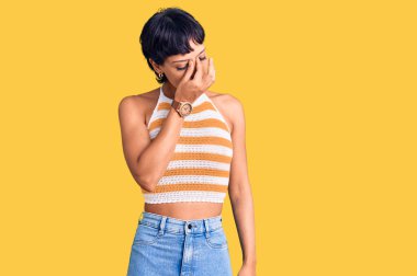 Kısa saçlı esmer bir kadın günlük kıyafetler giyiyor. Yorgun, burnu ve gözleri ovuşturuyor. Yorgun ve baş ağrısı çekiyor. Stres ve hüsran kavramı. 