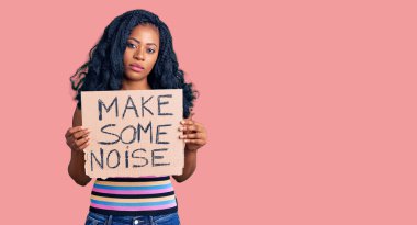 Beautiful african american woman holding make some noise banner thinking attitude and sober expression looking self confident  clipart