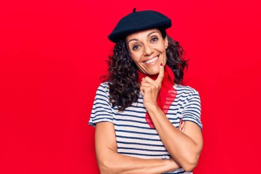 Fransız beresi takan orta yaşlı güzel bir kadın kameraya kollarını kavuşturmuş ve çenesi üzerinde kendinden emin bir şekilde bakıyor. Olumlu düşünmek. 