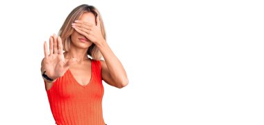 Güzel, beyaz bir kadın, günlük kıyafetler giyiyor, elleriyle gözlerini kapatıyor ve üzgün ve korku ifadeleriyle jestler yapıyor. utangaç ve olumsuz kavram. 