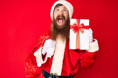 Uzun sakallı yakışıklı genç adam Noel Baba kostümü giyiyor ve hediye dolu büyük çanta sinirli ve öfkeli çığlıklar atıyor öfkeyle bağırıyor.. 