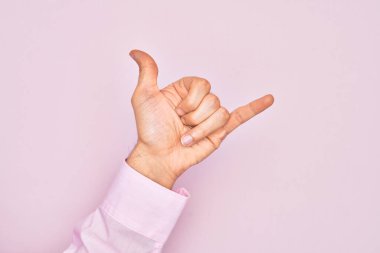 Kafkas genci parmaklarını izole edilmiş pembe arka planda gösteriyor Hawaii Shaka selamlama hareketi, telefon ve iletişim sembolü.