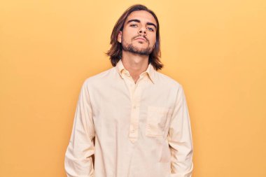 İş kıyafetleri giyen genç yakışıklı adam yüzünde ciddi bir ifadeyle rahatlamış. Basit ve doğal bir şekilde kameraya bakıyorsun.. 