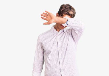 İş kıyafetleri giymiş, gözlük takmış, gözleri kollarıyla kapamış, ciddi ve üzgün görünen genç bir adam. Görme, saklama ve reddetme konsepti 