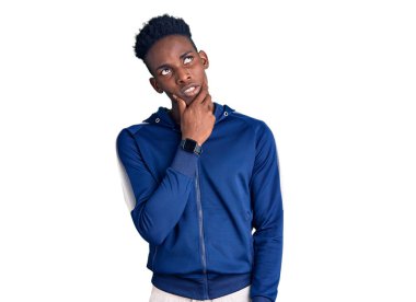 Spor giyimli genç Afro-Amerikalı bir adam bir soru hakkında endişeli ve gergin bir şekilde düşünüyor. 