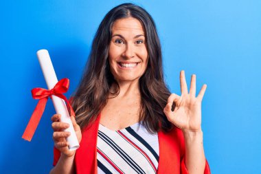 Genç, güzel, esmer, zeki, diploması mavi arka planda olan bir kadın. Parmaklarıyla işaret veriyor, gülümsüyor. Mükemmel bir sembol.