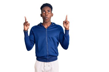 Genç Afro-Amerikan erkek spor giyer şaşırır, şaşırır ve parmaklarıyla işaret eder ve kollarını kaldırır. 