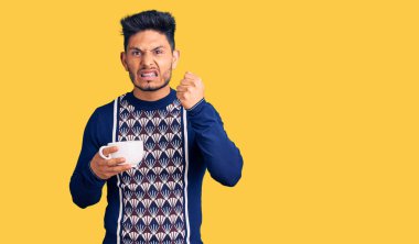 Yakışıklı Latin Amerikalı bir fincan kahve içen sinirli ve sinirli genç adam öfkeyle bağırıyor, öfkeyle çılgınca bağırıyor ve el kaldırıyor. 