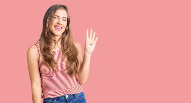 Güzel, beyaz, günlük kıyafetler giyen, dört numaralı parmaklarıyla işaret eden, kendinden emin ve mutlu bir şekilde gülümseyen bir kadın.. 