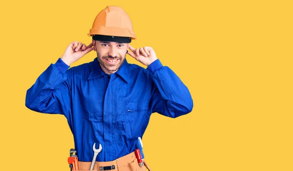 Joven Hispano Vistiendo Uniforme Obrero Sonriendo Tirando Las Orejas Con —  Fotos de Stock