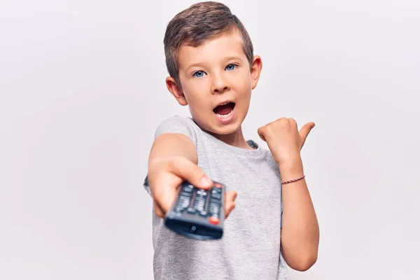 Cute Blond Kid Holding Television Remote Control Pointing Thumb Side — ストック写真