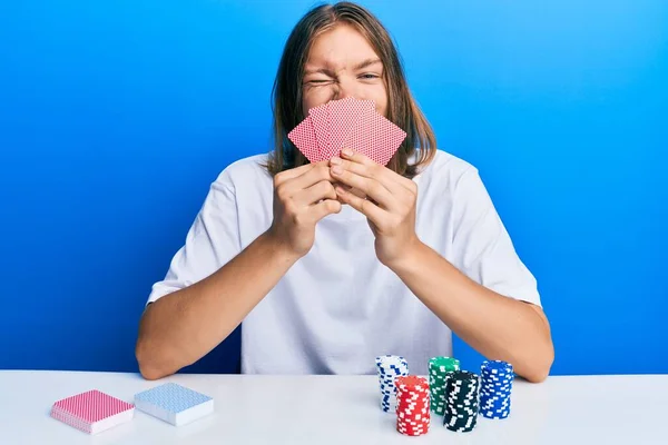 Uzun Saçlı Kumarda Poker Oynayan Yüzünü Kartlarla Kaplayan Yakışıklı Beyaz — Stok fotoğraf