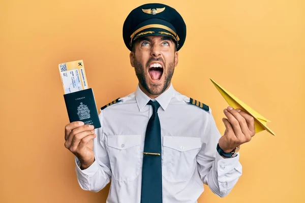 Handsome Hispanic Pilot Man Holding Paper Plane Passport Angry Mad — Stock Photo, Image