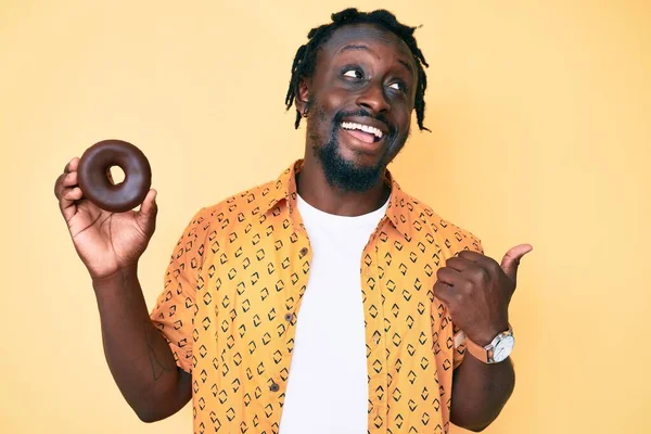 Jovem Afro Americano Com Tranças Segurando Donut Apontando Polegar Até — Fotografia de Stock