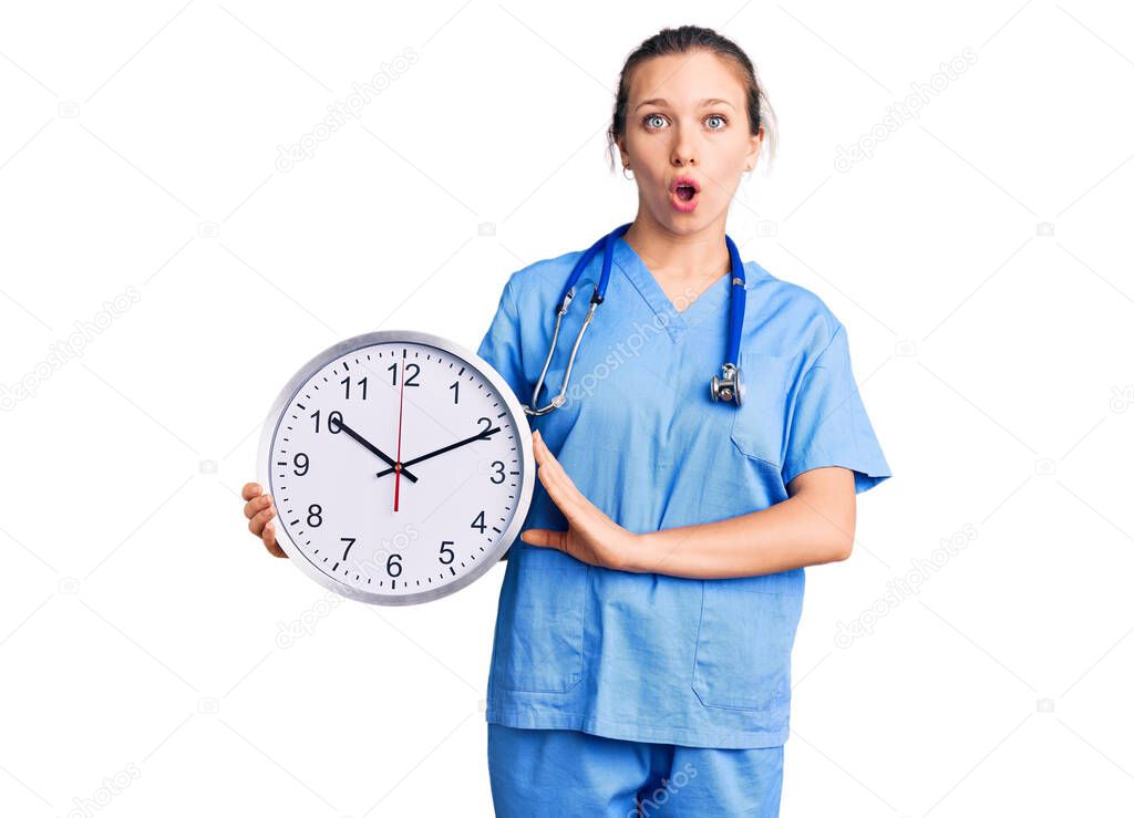Young beautiful blonde woman wearing doctor uniform and stethoscope scared and amazed with open mouth for surprise, disbelief face 