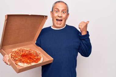 Gri saçlı son sınıf öğrencisi elinde teslimat kutusu olan İtalyan pizzası başparmağını kaldırıyor ve ağzı açık gülümsüyor. 