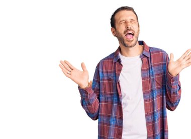 Gündelik kıyafetler giyen genç, çılgın ve çılgın başarıyı kutlayan kollarını kaldırmış, gözlerini kapatmış heyecanlı çığlıklar atan yakışıklı bir adam. Kazanan konsept 