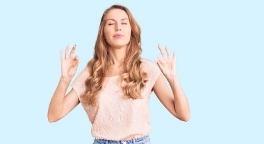 Sarışın, rahat kıyafetler giyen, gözleri kapalı gülümseyen, meditasyon hareketi yapan, güzel, beyaz bir kadın. yoga konsepti. 