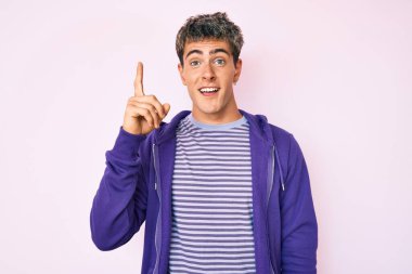 Sıradan mor bir kazak giyen yakışıklı genç adam başarılı bir fikri işaret ediyor. Heyecanlı ve mutlu. Bir numara.. 