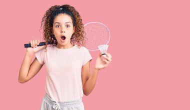 Kıvırcık saçlı, elinde badminton raketi olan güzel bir kız çocuğu. Mekik siki korkmuş ve ağzı açık kalmış, şaşırmış, inançsız bir yüz. 