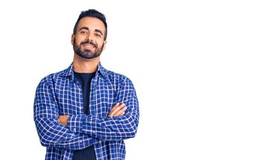 Gündelik kıyafetler giyen, kollarını kavuşturup kameraya gülümseyen genç İspanyol adam. pozitif kişi. 