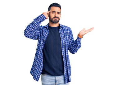 Gündelik giysiler giyen genç İspanyol adam avuç içi açık fotokopi alanı gösterip alnını işaret etmekten rahatsız oluyor. Bunu bir düşün.. 