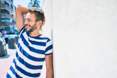 Sakallı yakışıklı beyaz adam, dışarıda mutlu bir şekilde gülümsüyor.