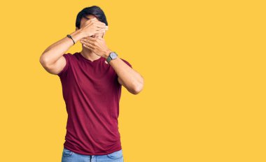 Yakışıklı, sıradan kıyafetler giyen, gözleri ve ağzı elleri ile kaplayan, şaşırmış ve şok olmuş bir İspanyol. duygu gizleme 