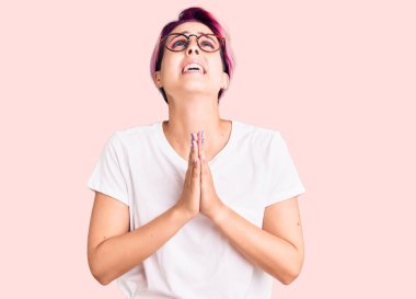 Pembe saçlı, sıradan kıyafetler giyen, gözlüklü, elleri bağlı, yalvaran, dua eden yüzünde umut ifadesi olan genç ve güzel bir kadın. Çok duygusal ve endişeli. Yalvarıyor. 