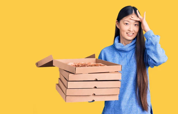 若いです美しい中国人女性保持段ボール箱のイタリアのピザ強調し 頭の上に手で不満 驚きと怒りの顔 — ストック写真
