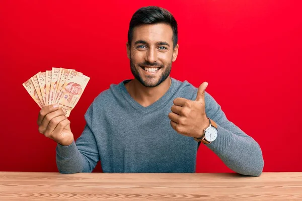 Hombre Hispano Guapo Sosteniendo Pesos Mexicanos Sonriendo Feliz Positivo Pulgar —  Fotos de Stock