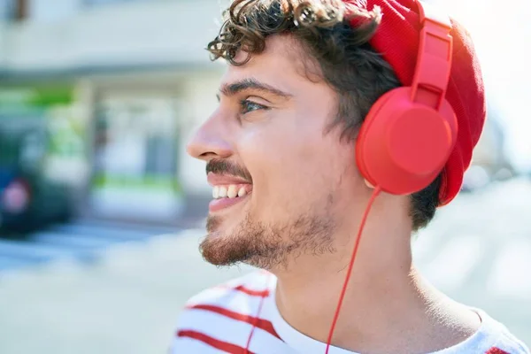若い白人男性の笑顔幸せな音楽を聴くためにヘッドフォンを使用して街を歩く — ストック写真
