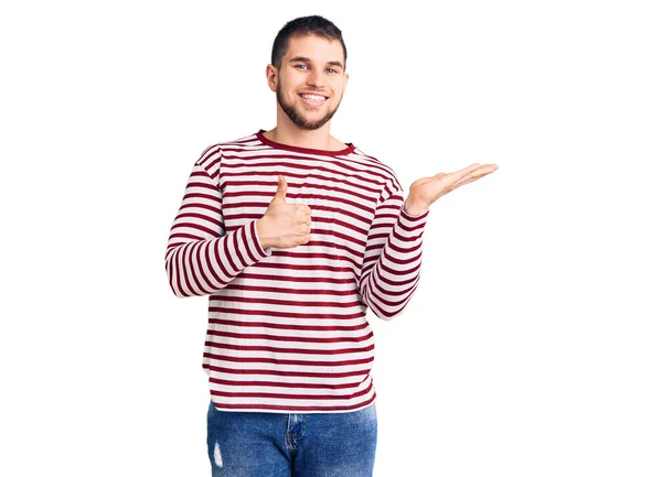 Jovem Homem Bonito Vestindo Camisola Listrada Mostrando Mão Palma Fazendo — Fotografia de Stock