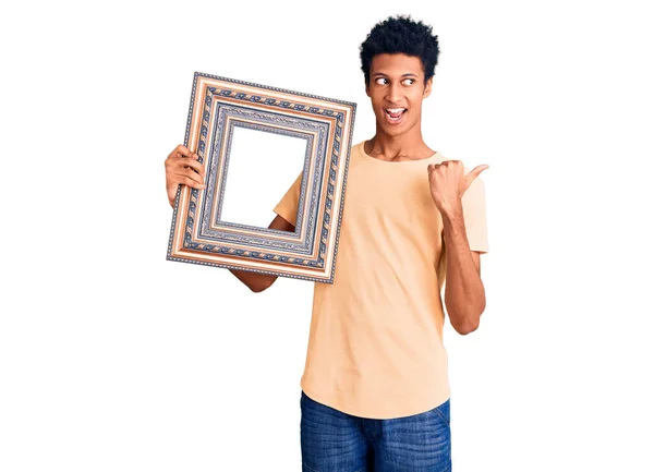 Young African American Man Holding Empty Frame Pointing Thumb Side — Stock Photo, Image