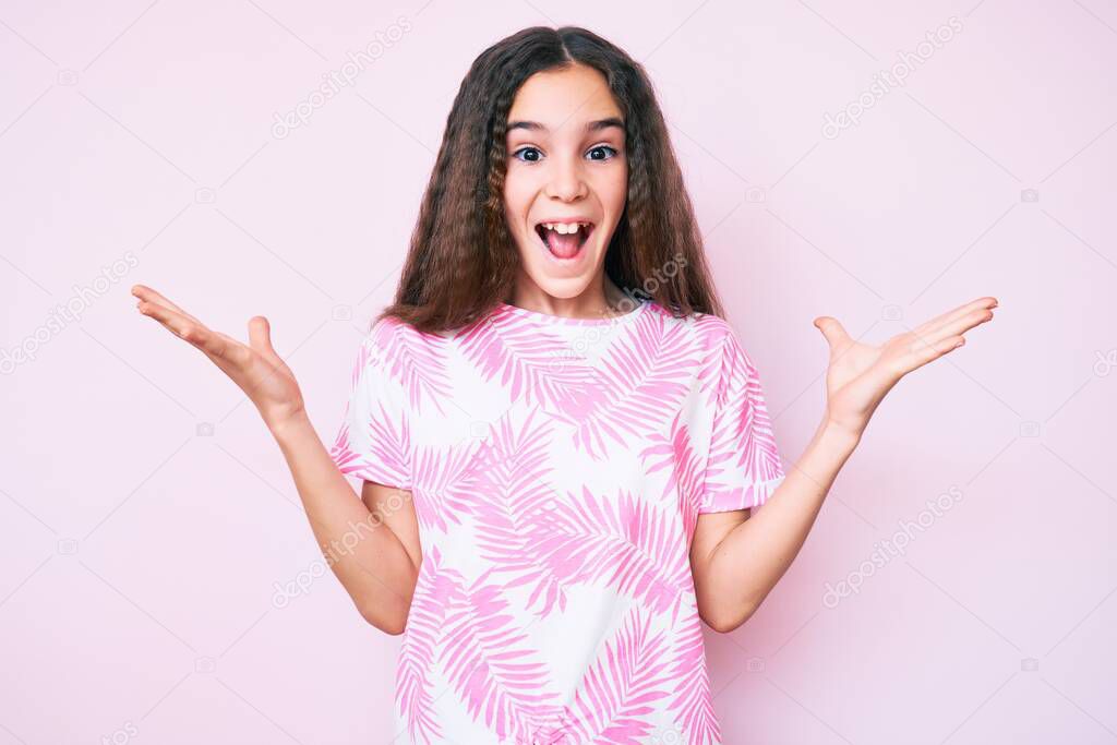 Cute hispanic child girl wearing casual clothes celebrating victory with happy smile and winner expression with raised hands 