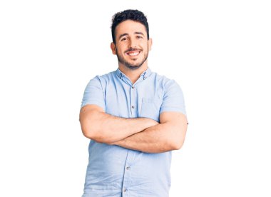 Gündelik kıyafetler giyen, kollarını kavuşturup kameraya gülümseyen genç İspanyol adam. pozitif kişi. 