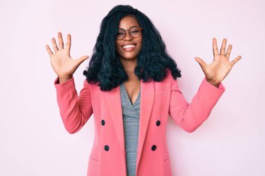 İş ceketi ve gözlük takan güzel Afrikalı kadın on numarayı gösterip işaret ederken kendinden emin ve mutlu bir şekilde gülümsüyor.. 