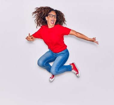 Orta yaşlı, güzel İspanyol bir kadın günlük kıyafetler ve mutlu bir gülümseme takınıyor. İzole edilmiş beyaz arka planda yüzünde gülümsemeyle zıpla