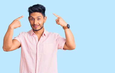 Yakışıklı Latin Amerikalı rahat bir yaz gömleği giyen genç adam iki eliyle başını gösteren gülümseme, harika fikir ya da düşünce, iyi hafıza 