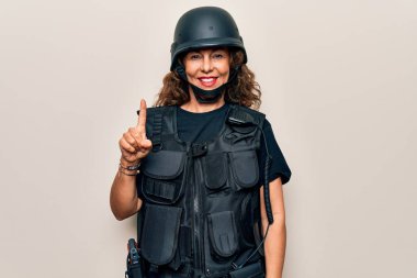 Orta yaşlı, güzel asker kadın kurşun geçirmez üniforma giyiyor ve güvenlik kaskı takıyor. Bir fikir veya soruyla gülümsüyor.