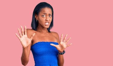 Genç Afro-Amerikalı kadın, günlük kıyafetlerini giymiş, korku ifadesinden korkmuş ve dehşete düşmüş. El hareketlerini durdur, şok içinde bağır. panik konsepti. 