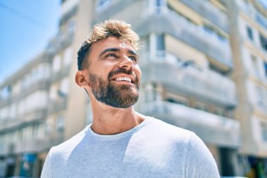 Genç İspanyol adam gülümseyerek şehirde mutlu bir şekilde yürüyor.