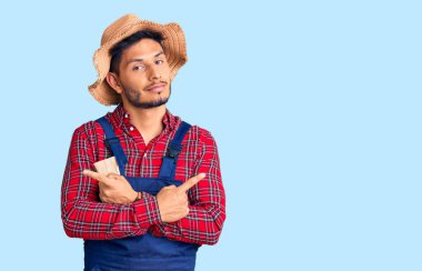 Yakışıklı Latin Amerikalı, giyimli, tamirci üniforması giyen, her iki tarafı da parmaklarıyla gösteren, farklı yönlü, farklı görüşlü genç adam. 