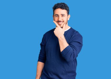 Gündelik kıyafetler giyen genç İspanyol adam kameraya kendinden emin bakıyor kollarını kavuşturup gülümsüyor ve çenesini kaldırıyor. Olumlu düşünmek. 